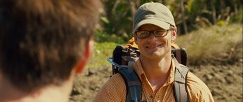 Movie still from “A Perfect Getaway” (2009), directed by David Twohy – A man wearing glasses and a hat is smiling; Close Up shot, Over the shoulder angle