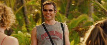 Movie still from “A Perfect Getaway” (2009), directed by David Twohy – A man in a gray shirt is smiling for the camera; Close Up shot, Over the shoulder angle