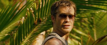 Movie still from “A Perfect Getaway” (2009), directed by David Twohy – A person wearing sunglasses near a palm tree; Close Up shot, Over the shoulder angle