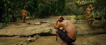 Movie still from “A Perfect Getaway” (2009), directed by David Twohy – A man sitting on the ground in the middle of a river; Wide shot, High angle