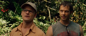 Movie still from “A Perfect Getaway” (2009), directed by David Twohy – A couple of men standing next to each other in a forest; Close Up shot, Over the shoulder angle