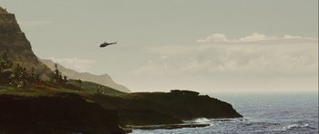 Movie still from “A Perfect Getaway” (2009), directed by David Twohy – A helicopter flying over the ocean near a rocky shore; Extreme Wide shot, Low angle