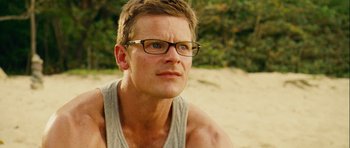 Movie still from “A Perfect Getaway” (2009), directed by David Twohy – A person wearing glasses with trees in the background; Close Up shot, Low angle