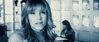 Movie still from “A Perfect Getaway” (2009), directed by David Twohy – A woman with long hair and bangs looking at the camera with another woman in the background; Close Up shot, Over the shoulder angle