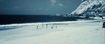 Movie still from “A Perfect Getaway” (2009), directed by David Twohy – A group of people standing on top of a sandy beach; Extreme Wide shot, High angle