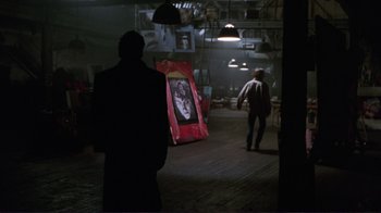 Movie still from “A Perfect Murder” (1998), directed by Andrew Davis – A man standing next to a painting in a dark room; Wide shot, Over the shoulder angle