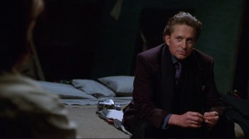Movie still from “A Perfect Murder” (1998), directed by Andrew Davis – A man sitting on a bed in a suit and tie; Medium shot, Over the shoulder angle