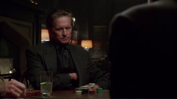 Movie still from “A Perfect Murder” (1998), directed by Andrew Davis – A man sitting at a table in front of a glass of water; Medium shot, Over the shoulder angle