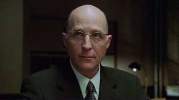 Movie still from “A Perfect Murder” (1998), directed by Andrew Davis – A man in a suit and tie wearing glasses; Close Up shot, Low angle