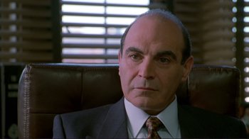 Movie still from “A Perfect Murder” (1998), directed by Andrew Davis – A man in a suit and tie sitting in a leather chair; Close Up shot, Over the shoulder angle