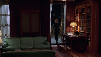 Movie still from “A Perfect Murder” (1998), directed by Andrew Davis – A person standing in a living room at night looking out a window; Wide shot, High angle