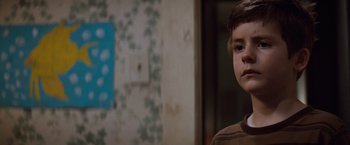 Movie still from “A Perfect World” (1993), directed by Clint Eastwood – A young boy standing next to a wall in a room; Close Up shot, Over the shoulder angle