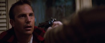 Movie still from “A Perfect World” (1993), directed by Clint Eastwood – A man holding a gun in his hand and looking at the camera; Close Up shot, Over the shoulder angle