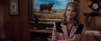 Movie still from “A Perfect World” (1993), directed by Clint Eastwood – A woman wearing a pink and black jacket in front of a painting of a bull; Medium shot, Over the shoulder angle