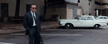 Movie still from “A Perfect World” (1993), directed by Clint Eastwood – A man in a suit and sunglasses walking down the street; Wide shot, Low angle