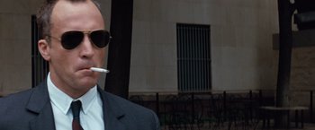 Movie still from “A Perfect World” (1993), directed by Clint Eastwood – A man in a suit and sunglasses smoking a cigarette; Close Up shot, Low angle