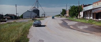 Movie still from “A Perfect World” (1993), directed by Clint Eastwood – An old car is driving down the street; Extreme Wide shot, High angle