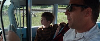 Movie still from “A Perfect World” (1993), directed by Clint Eastwood – A young boy sitting on a bus next to an older man; Medium shot, Over the shoulder angle