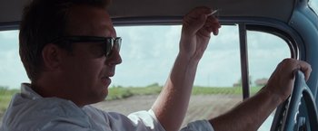 Movie still from “A Perfect World” (1993), directed by Clint Eastwood – A man holding a cigarette while sitting in a car; Close Up shot, Over the shoulder angle