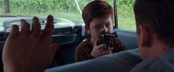 Movie still from “A Perfect World” (1993), directed by Clint Eastwood – A young boy holding a gun in a car; Close Up shot, Over the shoulder angle