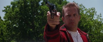 Movie still from “A Perfect World” (1993), directed by Clint Eastwood – A man holding a gun in his right hand while wearing a red jacket; Close Up shot, Low angle