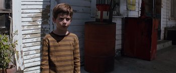 Movie still from “A Perfect World” (1993), directed by Clint Eastwood – A young boy standing in front of a barrel; Medium shot, Over the shoulder angle