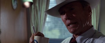 Movie still from “A Perfect World” (1993), directed by Clint Eastwood – An older man wearing a white hat holding a cup of coffee; Close Up shot, Over the shoulder angle