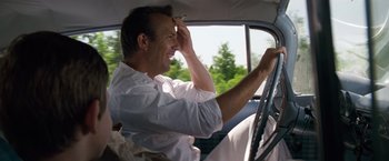 Movie still from “A Perfect World” (1993), directed by Clint Eastwood – A man sitting in the driver's seat of a car; Medium shot, Over the shoulder angle