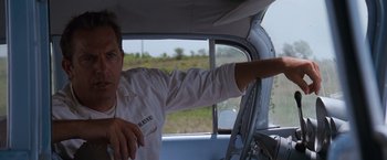 Movie still from “A Perfect World” (1993), directed by Clint Eastwood – A man driving a car in the middle of a field; Close Up shot, Low angle