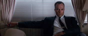 Movie still from “A Perfect World” (1993), directed by Clint Eastwood – A man in a suit and tie sitting in front of a window; Close Up shot, Low angle
