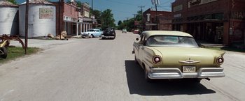 Movie still from “A Perfect World” (1993), directed by Clint Eastwood – An old yellow car driving down a street; Wide shot, Low angle