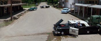Movie still from “A Perfect World” (1993), directed by Clint Eastwood – An old car is parked on the side of the road; Extreme Wide shot, High angle