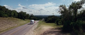 Movie still from “A Perfect World” (1993), directed by Clint Eastwood – An airstream traveling down a road in the middle of the day; Extreme Wide shot, High angle