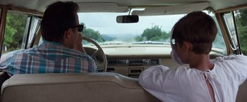 Movie still from “A Perfect World” (1993), directed by Clint Eastwood – Two men are sitting in the back seat of a car; Medium shot, Over the shoulder angle