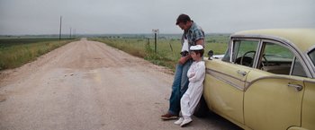 Movie still from “A Perfect World” (1993), directed by Clint Eastwood – A man and a boy sitting on the side of the road; Wide shot, Over the shoulder angle