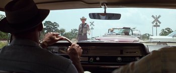 Movie still from “A Perfect World” (1993), directed by Clint Eastwood – A man in a cowboy hat is driving a car; Medium shot, Over the shoulder angle