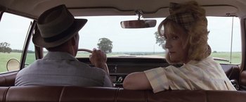 Movie still from “A Perfect World” (1993), directed by Clint Eastwood – A man and a woman sitting in the back seat of a car; Medium shot, Over the shoulder angle