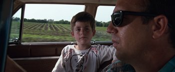 Movie still from “A Perfect World” (1993), directed by Clint Eastwood – A man and a boy sitting in the back of a car; Close Up shot, Over the shoulder angle