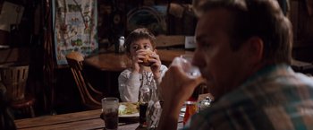 Movie still from “A Perfect World” (1993), directed by Clint Eastwood – A man and a boy sitting at a table eating a hamburger; Medium shot, Over the shoulder angle