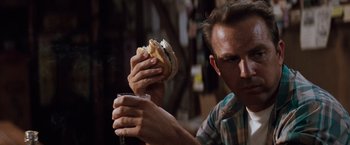 Movie still from “A Perfect World” (1993), directed by Clint Eastwood – A man is holding a sandwich and a glass of water; Close Up shot, Low angle