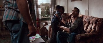 Movie still from “A Perfect World” (1993), directed by Clint Eastwood – A group of people sitting in a living room; Medium shot, Over the shoulder angle