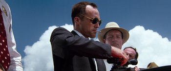 Movie still from “A Perfect World” (1993), directed by Clint Eastwood – A man in a suit and sunglasses holding a gun; Medium shot, Low angle