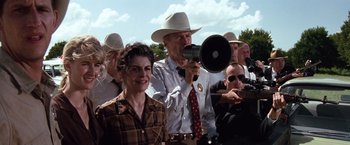 Movie still from “A Perfect World” (1993), directed by Clint Eastwood – A group of people standing in a field with a man holding a megaphone; Medium shot, Low angle