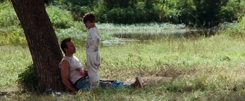 Movie still from “A Perfect World” (1993), directed by Clint Eastwood – A man and a boy sitting in the grass; Wide shot, Over the shoulder angle