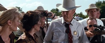 Movie still from “A Perfect World” (1993), directed by Clint Eastwood – A group of people standing next to each other on a street; Medium shot, Over the shoulder angle