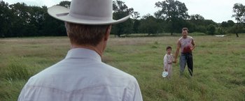 Movie still from “A Perfect World” (1993), directed by Clint Eastwood – A man and a woman in a field with a frisbee; Wide shot, Over the shoulder angle