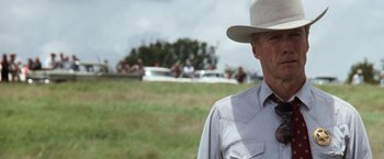 Movie still from “A Perfect World” (1993), directed by Clint Eastwood – An older man wearing a cowboy hat in a field; Close Up shot, Over the shoulder angle
