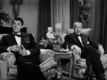 Movie still from “A Place in the Sun” (1951), directed by George Stevens – Two men sitting on a couch in a living room wearing tuxedos; Medium shot, High angle