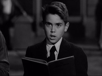 Movie still from “A Place in the Sun” (1951), directed by George Stevens – A boy in a suit and tie holding an open book; Close Up shot, Low angle