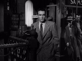 Movie still from “A Place in the Sun” (1951), directed by George Stevens – A black and white photo of a man in a suit and tie; Medium shot, Low angle